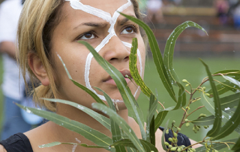 Person with face paint behind leaves